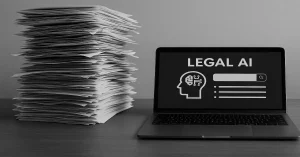 Papierstapel neben Laptop mit Legal AI Interface zur Vertragsanalyse